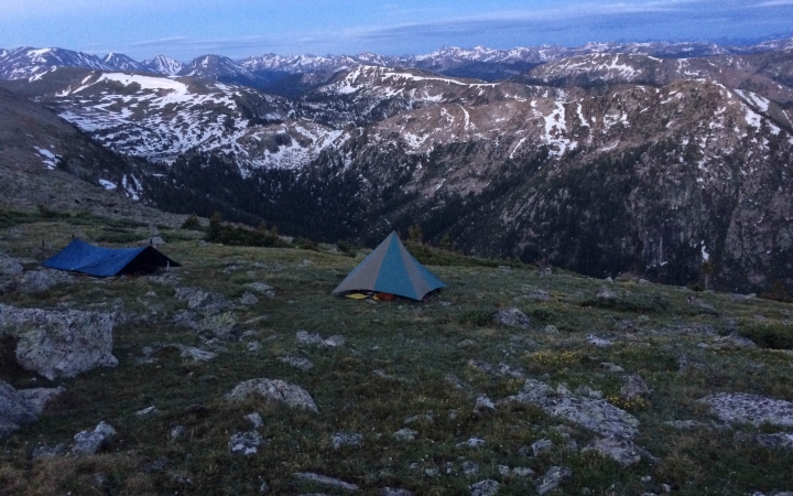 tents and shelters are set up high above a vast mountain landscape